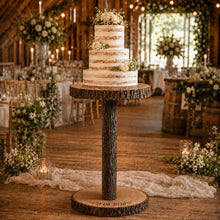 Load image into Gallery viewer, Personalised rustic wood log cake stand table with natural bark edges, tall 80cm pedestal support, engraved log slices and a four-tier semi-naked wedding cake displayed in a romantic garden wedding setting.
