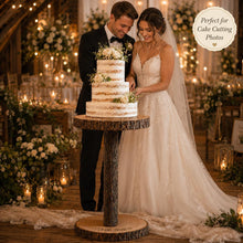 Load image into Gallery viewer, May include: A three-tiered naked wedding cake with white frosting between layers, topped with white flowers, resting on a rustic wooden cake stand with a bark-textured pedestal and a circular base engraved with the date 21.06.2026.

